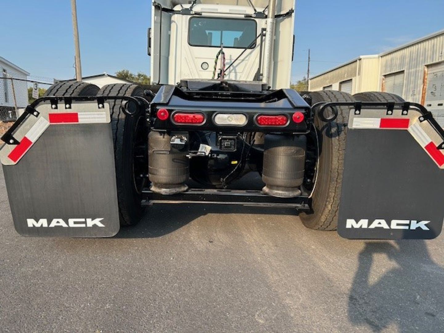 Mack AN64T tractor rear view showing dual turbofans and mud flaps with Mack logo, rear lighting, and hitch area.