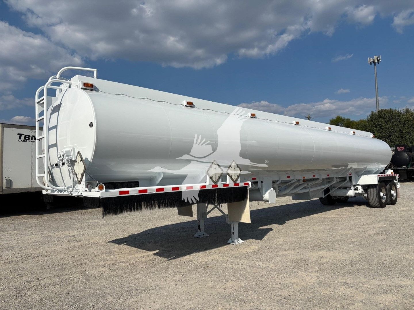 Horizontal cylindrical Heil 9200 gallon gas fuel trailer viewed from side with landing legs down and dual-axle rear, white primer with small safety rails.