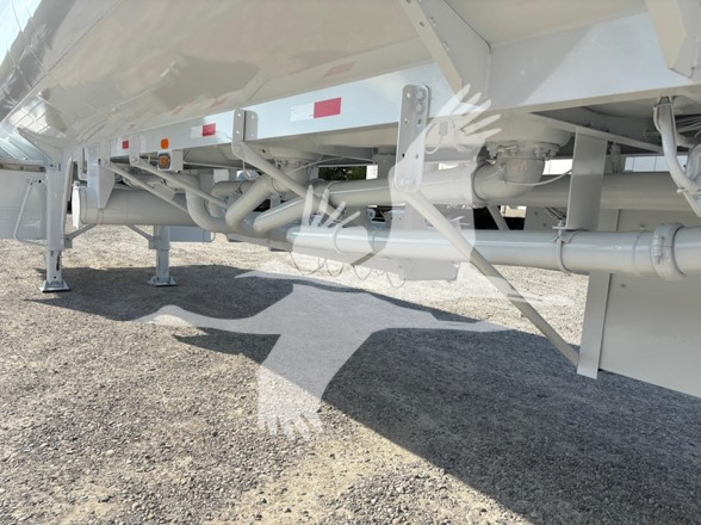 Trailer underside showing frame rails, suspension, and piping on Heil Dot406 trailer. Visible components include structural beams, cross members, support legs, hydraulic lines, and wheel/tire area partially visible.