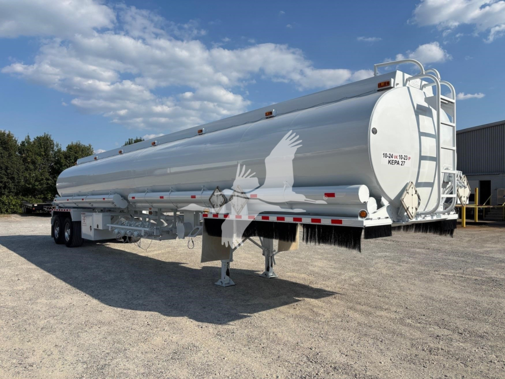 Fuel trailer showing cylindrical tank with rear ladder and support legs, 9200 gallon Heil tanker, white exterior, side warning decals, tandem axle dual wheels.