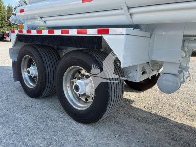 Heil 9200 gallon tanker trailer rear wheels and side frame showing dual rear tires, chrome hub, white tanker along with safety reflective tape and support structures.
