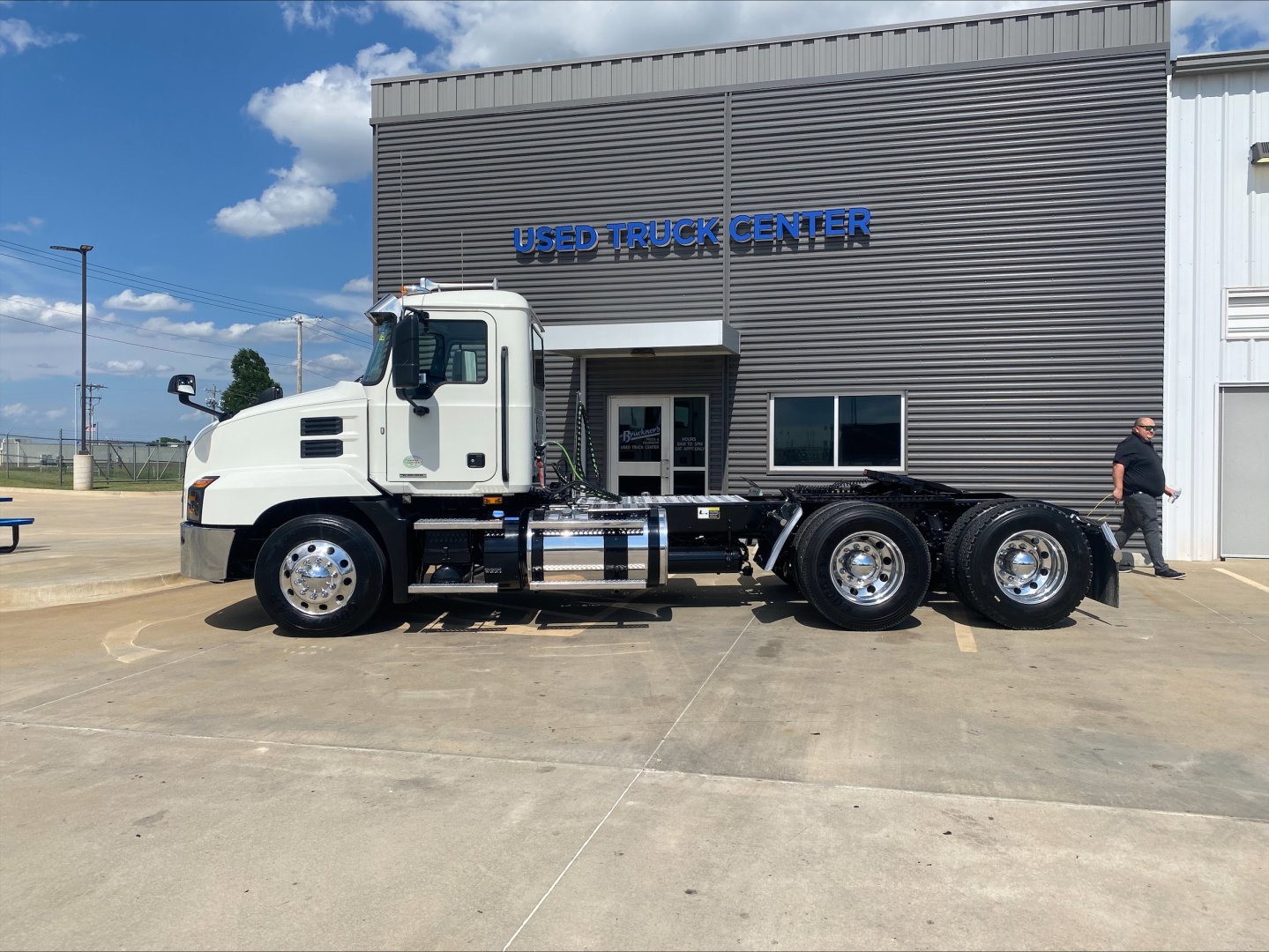 White 2021 Mack AN64T daycab truck with multiple axles parked in front of a Used Truck Center building; VIN 1M1AN2GY4MM022143 and stock number B3379P not visible in text on image.