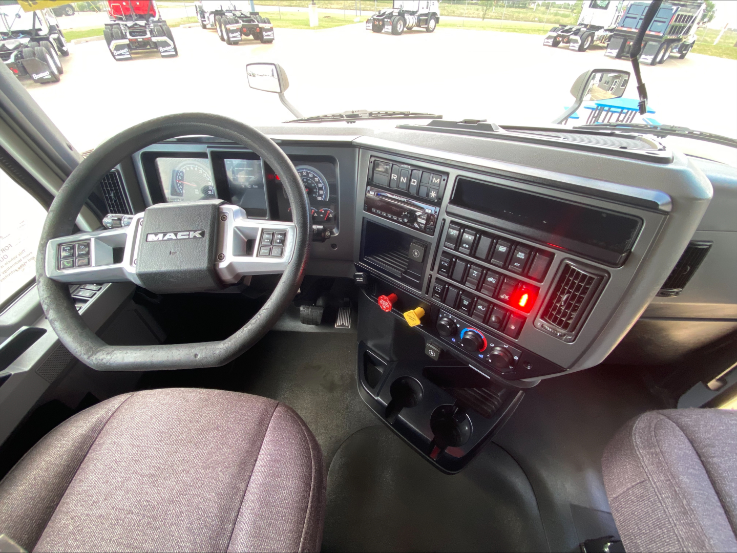 Mack AN64T cab interior showing steering wheel, dashboard with controls, and center console.