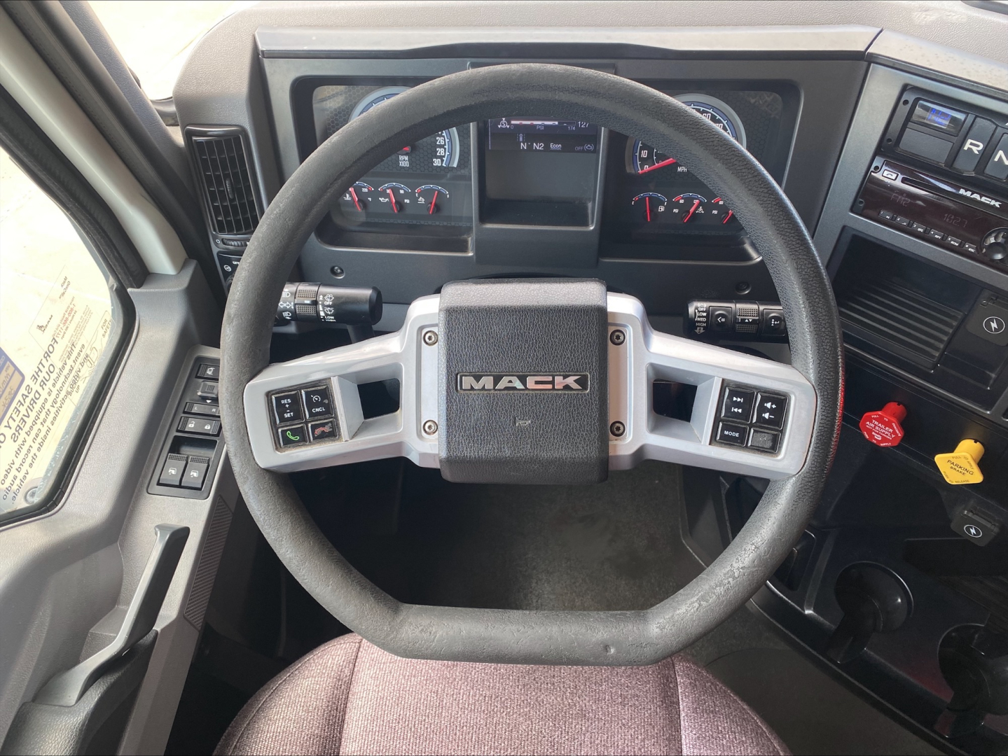 Mack AN64T dash and steering wheel interior showing Mack emblem on center of steering wheel with gauges in background