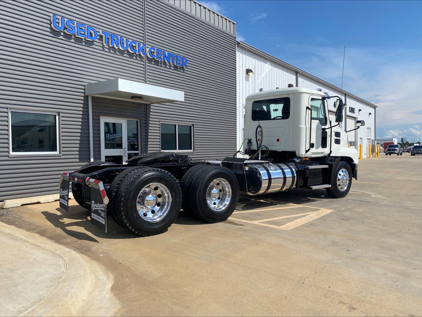 Mack AN64T truck chassis parked outside Used Truck Center showing tractor with white cab and dual rear axles.