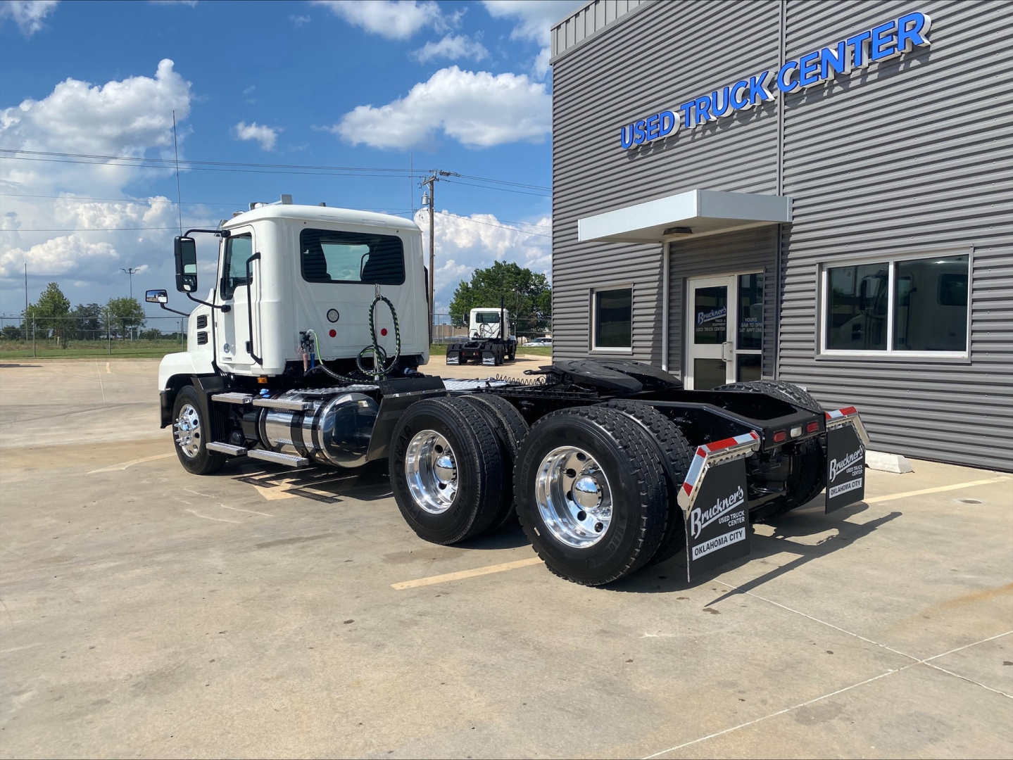 Mack AN64T truck tractor View showing side and rear of white cab with dual rear axles in a dealership lot.