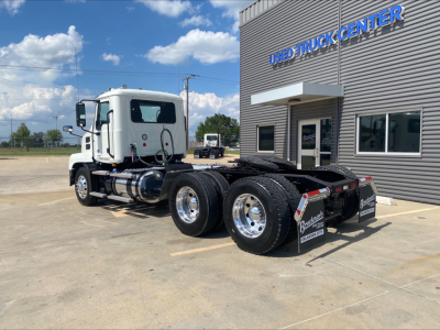 Mack AN64T truck tractor View showing side and rear of white cab with dual rear axles in a dealership lot.