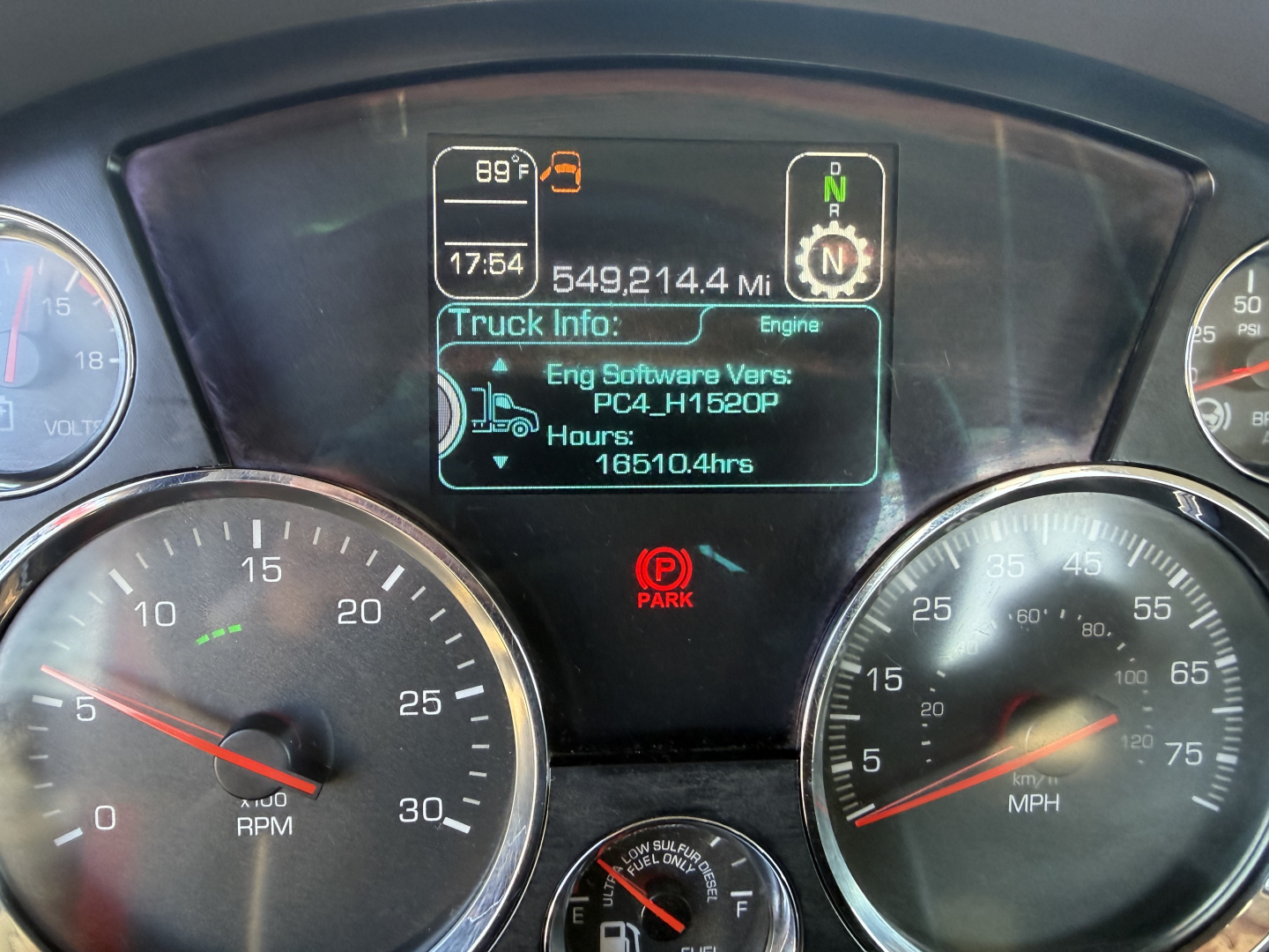 Dashboard display from a 2020 Kenworth T880 showing engine hours, mileage, and gear indicator. Central screen reads Eng Software Vers: PC4_H1520P Hours: 16510.4hrs, 549,214.4 Mi, Truck Info: Engine; Park indicator visible.