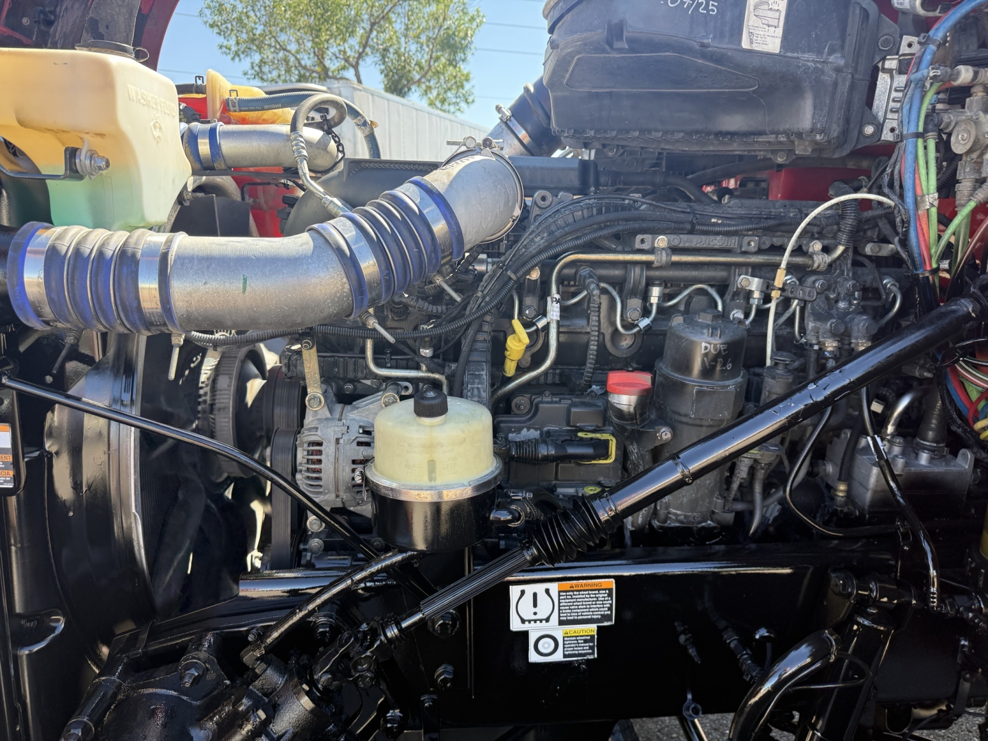 Kenworth T880 engine bay showing turbo hoses, fuel lines, and hydraulic reservoir with yellow cap.
