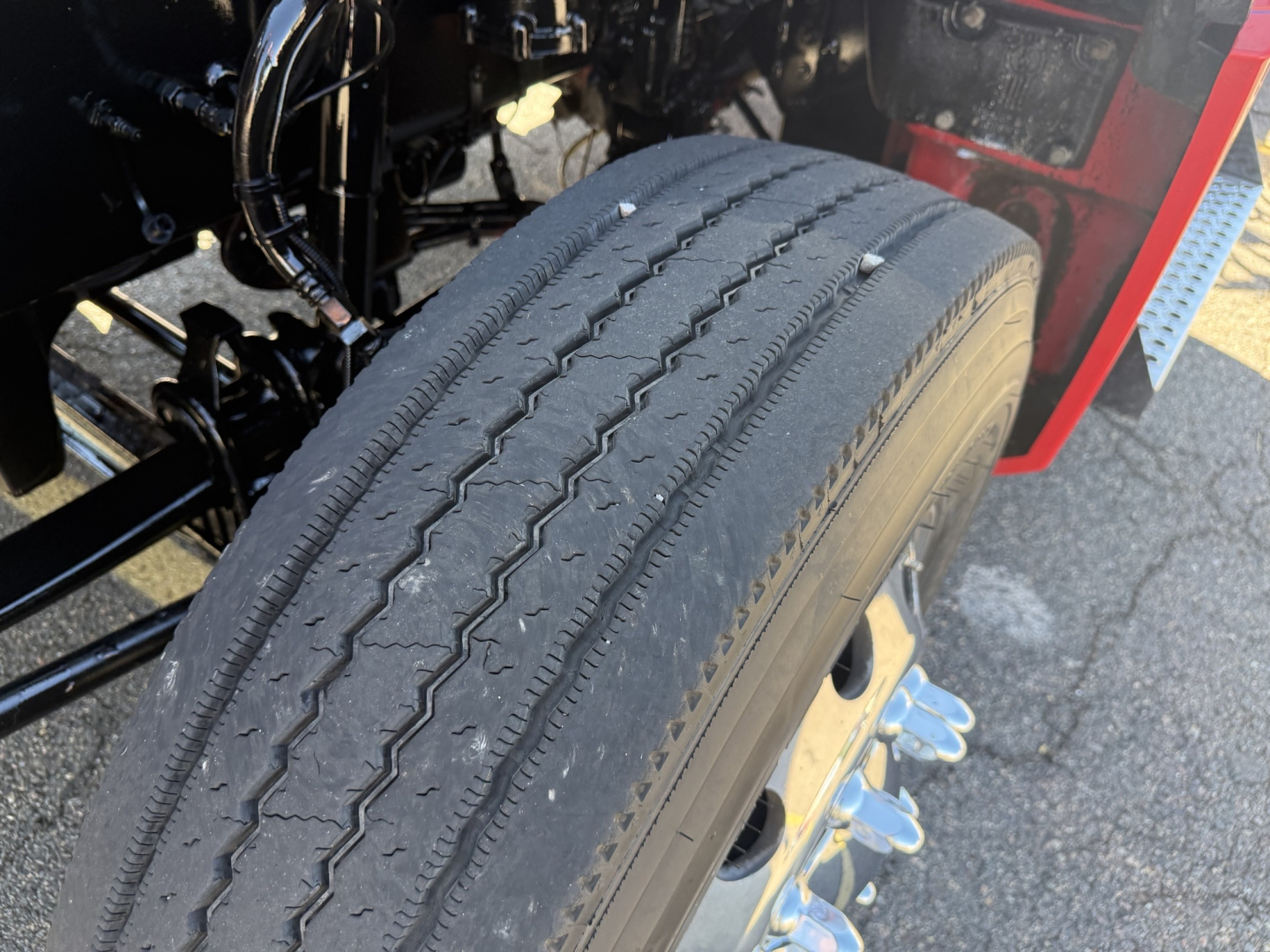 Rear front-left wheel well of a 2020 Kenworth T880 truck showing a single tire tread and suspension components.