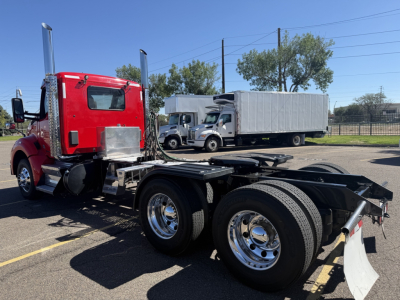 Kenworth T880 chassis cab with red cab and dual rear axles, side view showing empty fifth wheel area and chrome wheels.