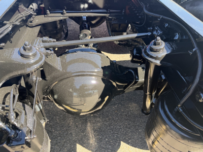 Kenworth T880 drive axle and suspension components under the chassis in a truck yard.