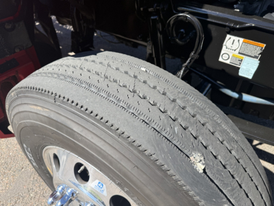 Wheel and tire on Kenworth T880 chassis with label stickers and engine bay visible in background.