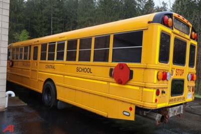 School bus side and rear view showing yellow IC Corporation CE Series bus with 'CENTRAL SCHOOL' markings, safety stop signs extended, and rear emergency doors.