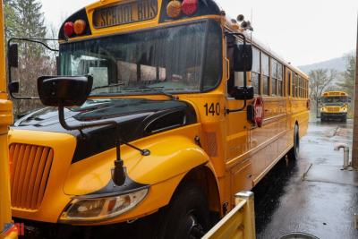 School bus front-left view with yellow IC Corporation CE Series, 140 number on door, 'School Bus' sign top, daytime parking lot.