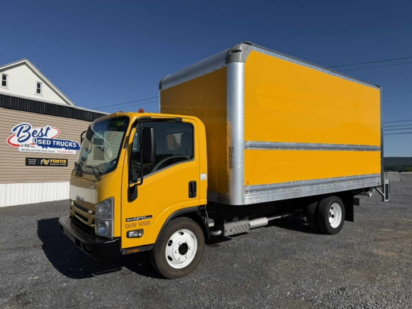 Isuzu NPR box truck in yellow with a bright yellow cargo box and silver framing, front view showing GVW 6450 label on door.
