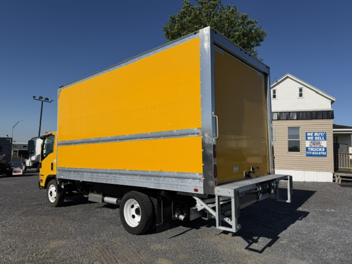 Isuzu NPR box truck with yellow cargo box and silver frame, rear loading ramp visible, side view.