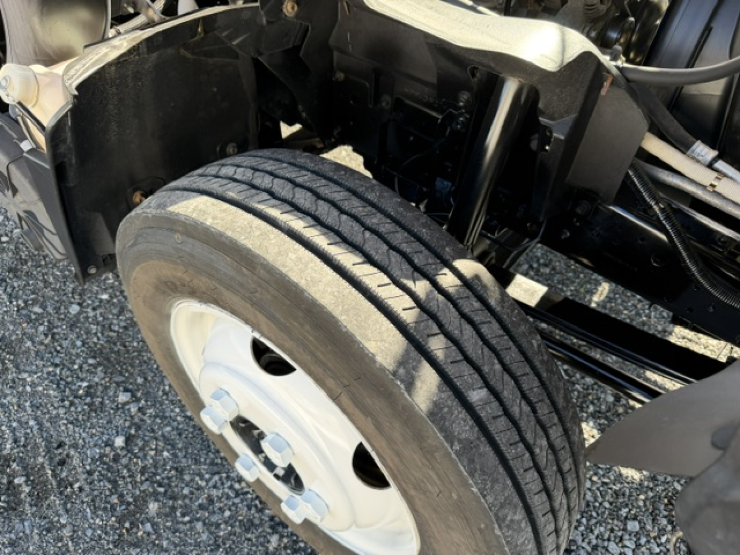 Isuzu NPR wheel and front suspension area showing dual front tires and wheel hub, part of a box truck chassis.