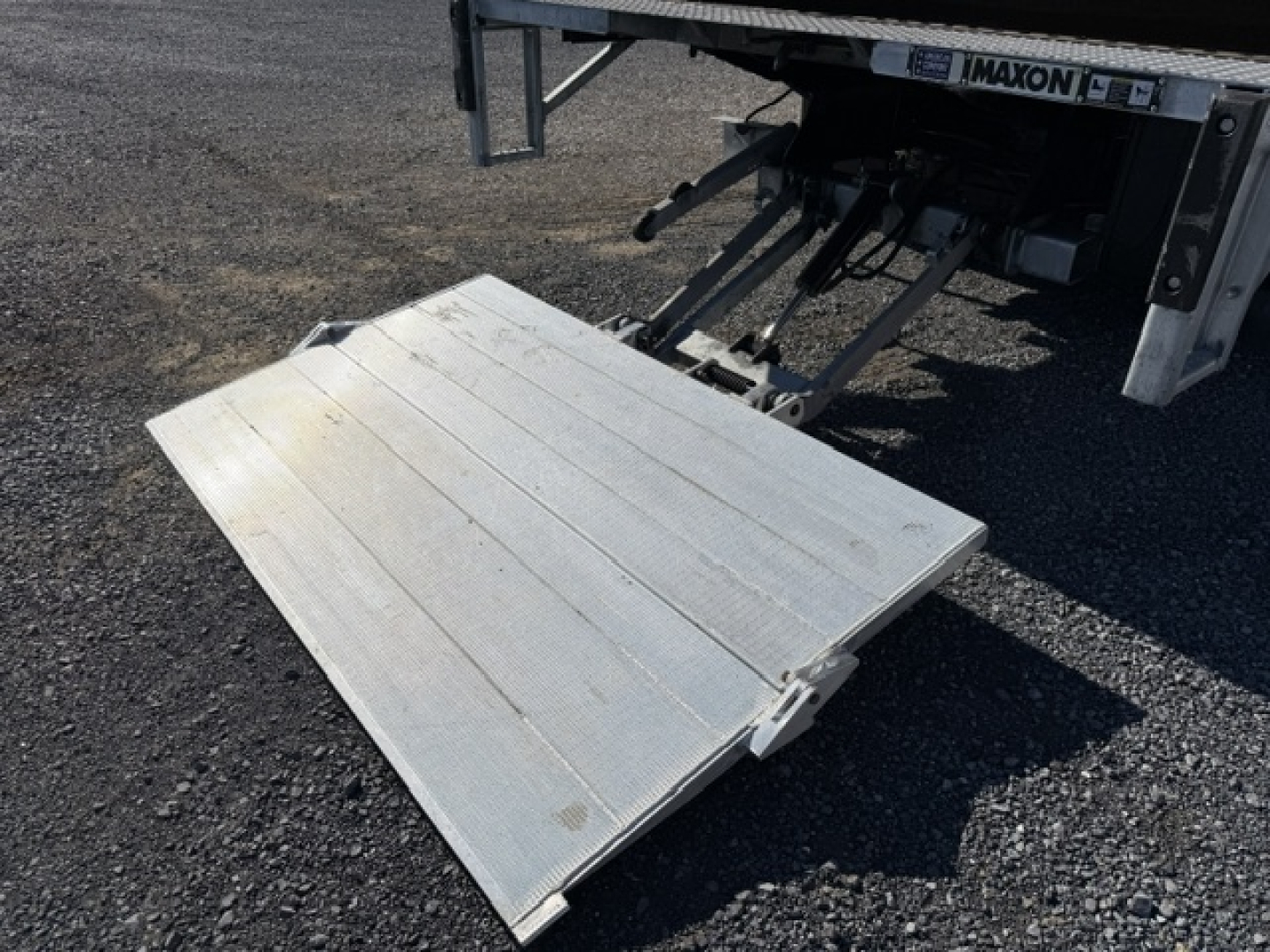 Isuzu NPR truck alignment with fold-out aluminum liftgate platform extended from rear of box truck showing IMAXON branding and hydraulic assembly.
