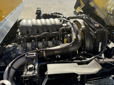Isuzu NPR engine bay showing intake manifold, turbocharger, air intake hoses, and surrounding components in a box truck cab; visible hoses and wiring harnesses.