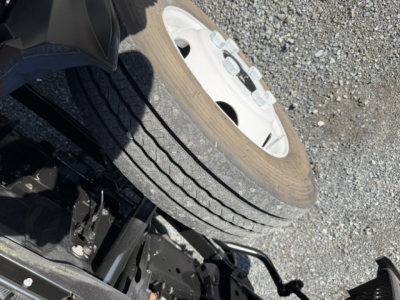 Isuzu NPR chassis with front wheel and tire, undercarriage components visible.