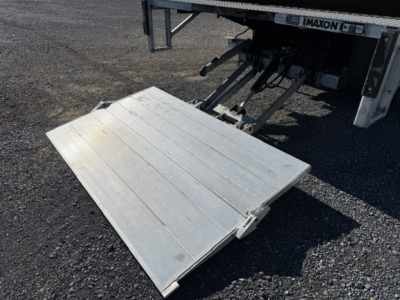 Isuzu NPR truck alignment with fold-out aluminum liftgate platform extended from rear of box truck showing IMAXON branding and hydraulic assembly.