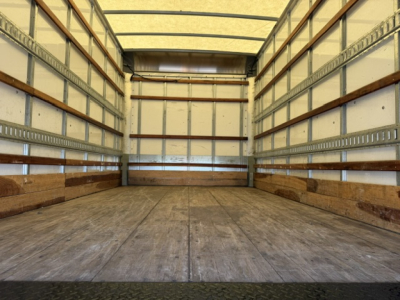 Isuzu NPR truck box interior showing empty cargo area with wooden side walls and metal rails.