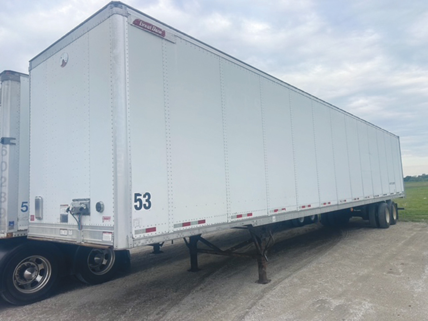 Great Dane plate van trailer in a used condition showing side panels and rear hitch, with wheel and landing gear visible.