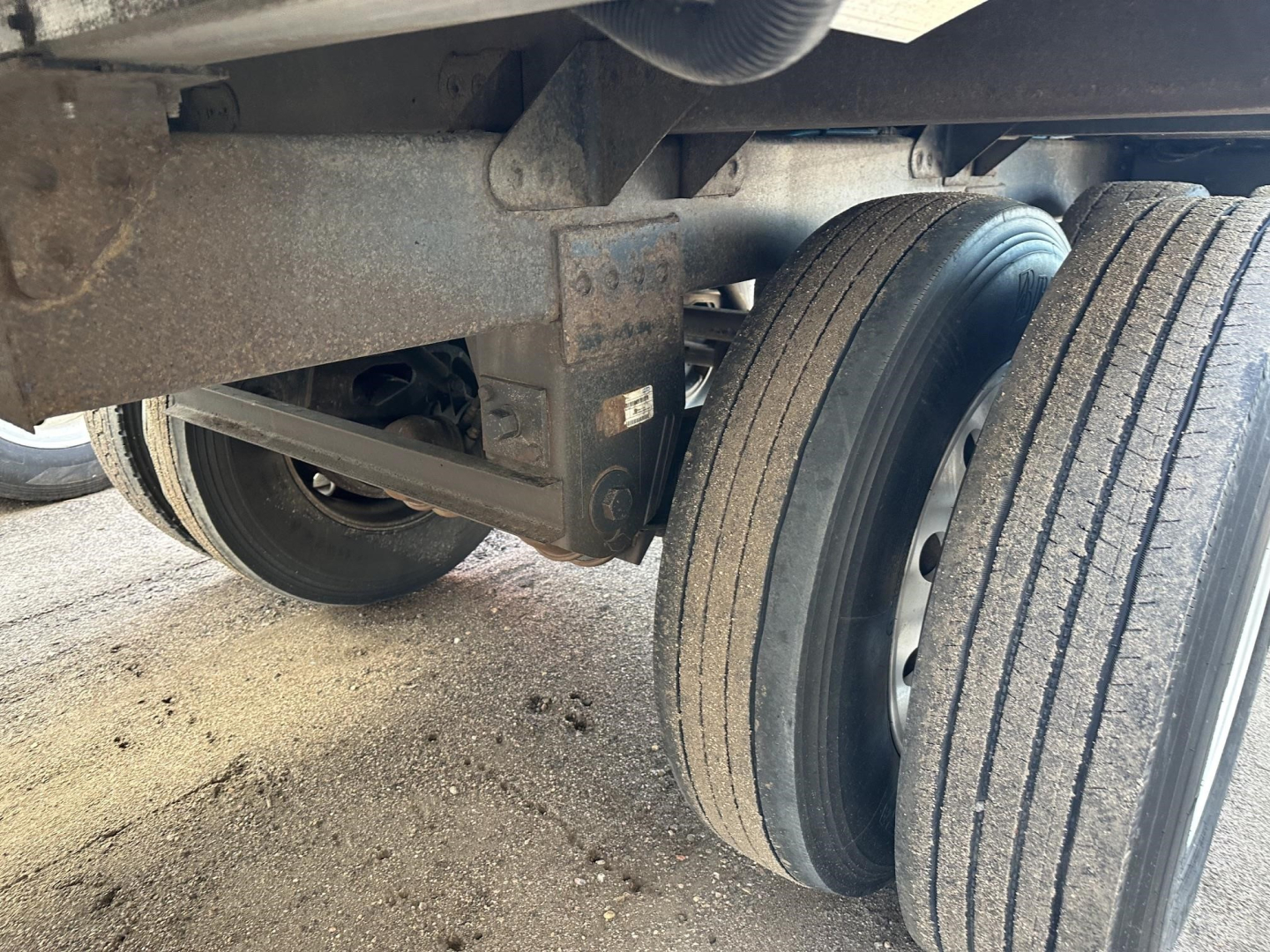 Trailer axle and wheels showing dual rear‑axle setup with heavy metal frame and leaf spring, 78 inch side hopper trailer