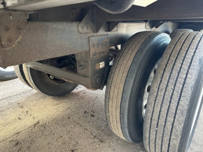 Trailer undercarriage with dual tires and suspension components visible; shows metal frame and wheel hubs.