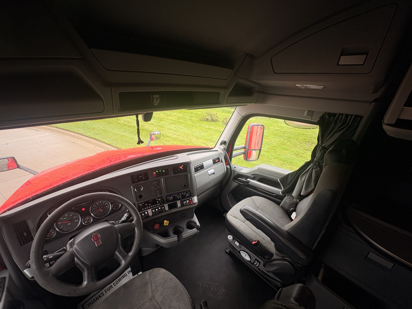 Kenworth T680 cab interior showing dashboard and steering wheel with controls and passenger seat.