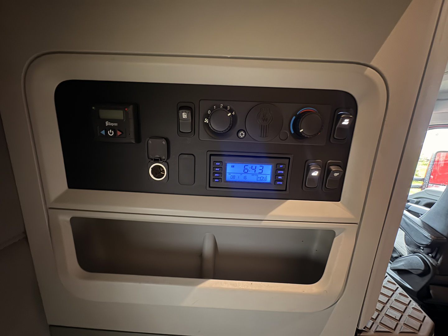 Kenworth T680 interior dash area showing instrument panel and control knobs with a blue digital display reading 6:43.