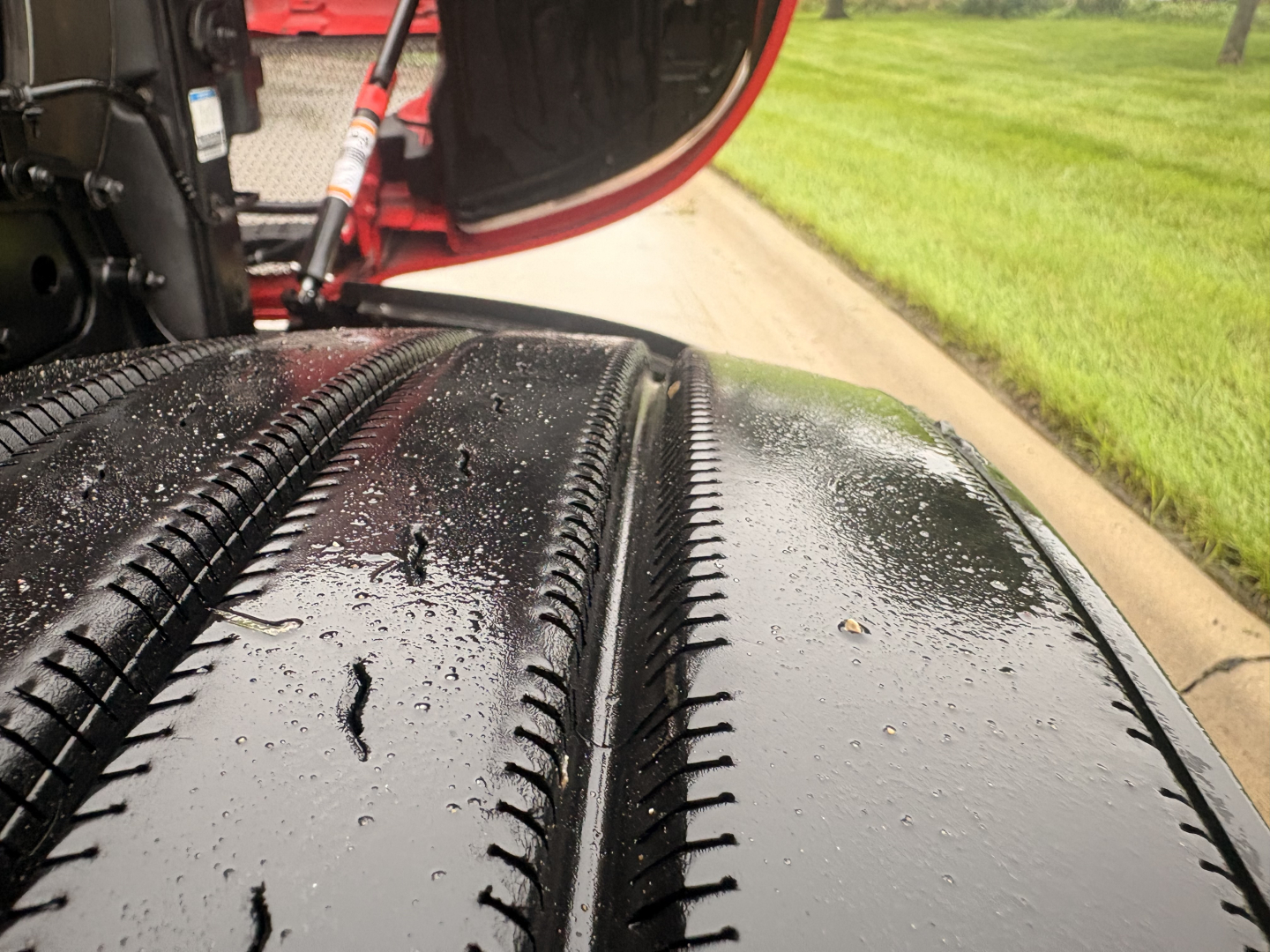 Tire treads on Kenworth T680 wheel well with rain droplets, part of a truck undercarriage visible.