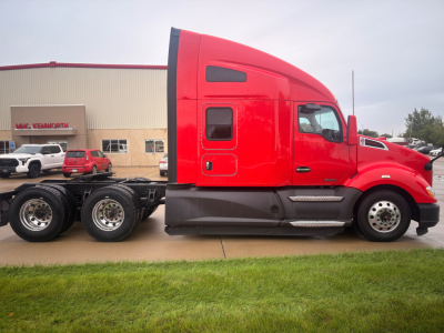 Kenworth T680 sleeper cab tractor side view showing bright red exterior and two-step entry, chassis with dual rear axles and wheels.