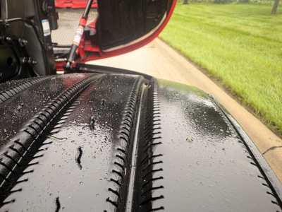 Tire treads on Kenworth T680 wheel well with rain droplets, part of a truck undercarriage visible.