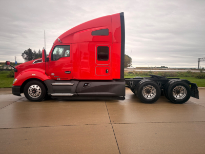 Kenworth T680 tractor with red cab in profile view showing side and rear wheels.