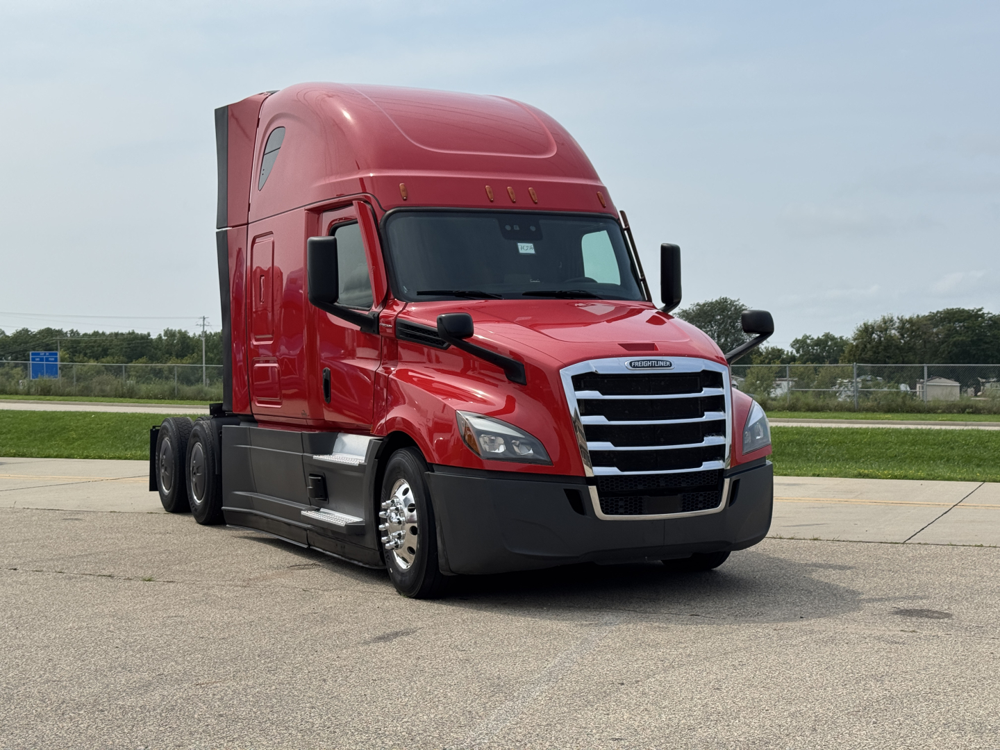 Freightliner Cascadia 126 truck cab in red, front view with chrome grille and black bumper, daytime outdoor lot