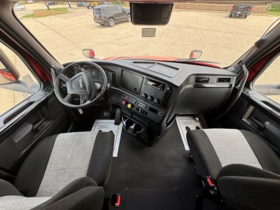 Cab interior of a 2023 Freightliner Cascadia 126 truck showing steering wheel, dashboard with controls, two front seats, and center console.