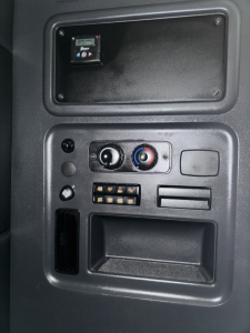 Panel and controls inside Freightliner Cascadia cab showing switch panel, circular climate controls, and storage pocket.