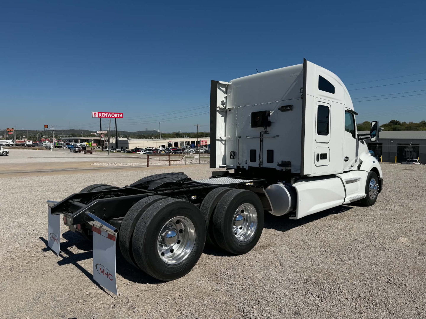 Kenworth T680 tractor rear-left view showing fifth wheel area, dual rear axles, and sleeper cab with white paint.