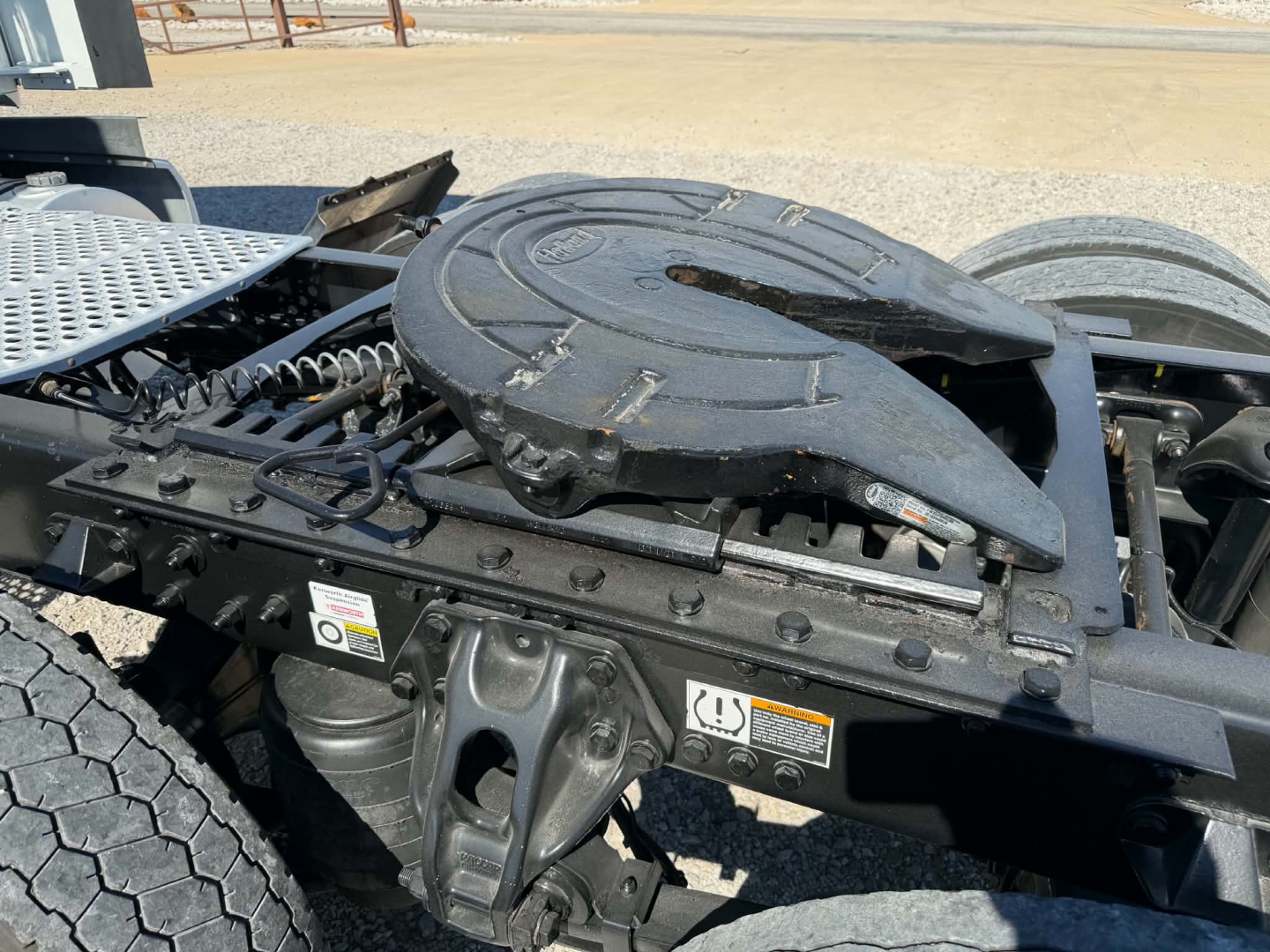 Kenworth T680 fifth wheel area with visible spare wheel carrier and frame components; no legible text other than stickers near the side rail.