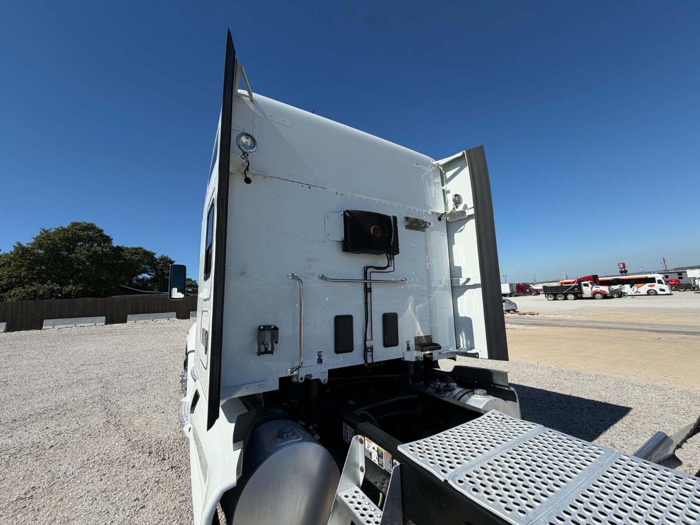 Kenworth T680 rear cab area showing sleeper truck with rear access door, fuel/air lines and chassis deck visible.