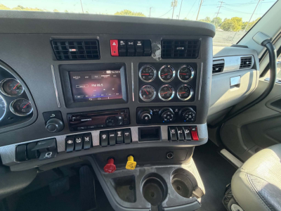 Kenworth T680 cabin dashboard view with steering column, multiple gauges, touchscreen display, and center console controls.