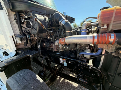 Kenworth T680 engine bay showing intake piping, turbocharger, coolant reservoir, and surrounding hoses in a side view under hood.