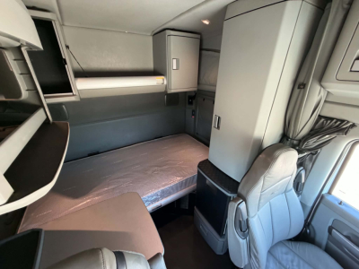 Kenworth T680 sleeper cab interior showing bunk bed and storage compartments.