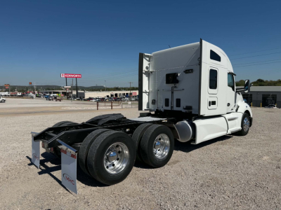 Kenworth T680 tractor rear-left view showing fifth wheel area, dual rear axles, and sleeper cab with white paint.