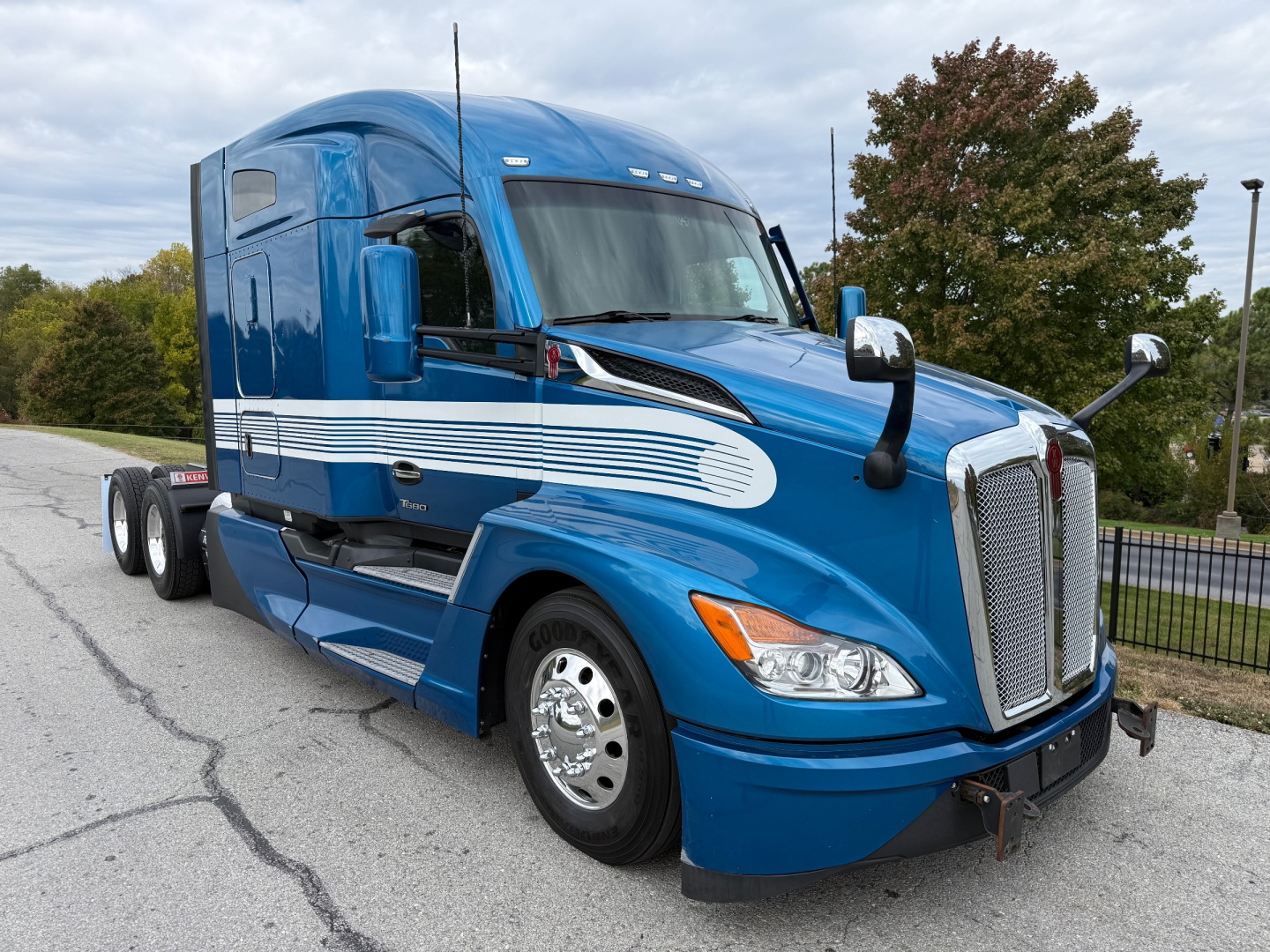 Kenworth T680 tractor in blue with white racing stripe showing side view and sleeper cab.