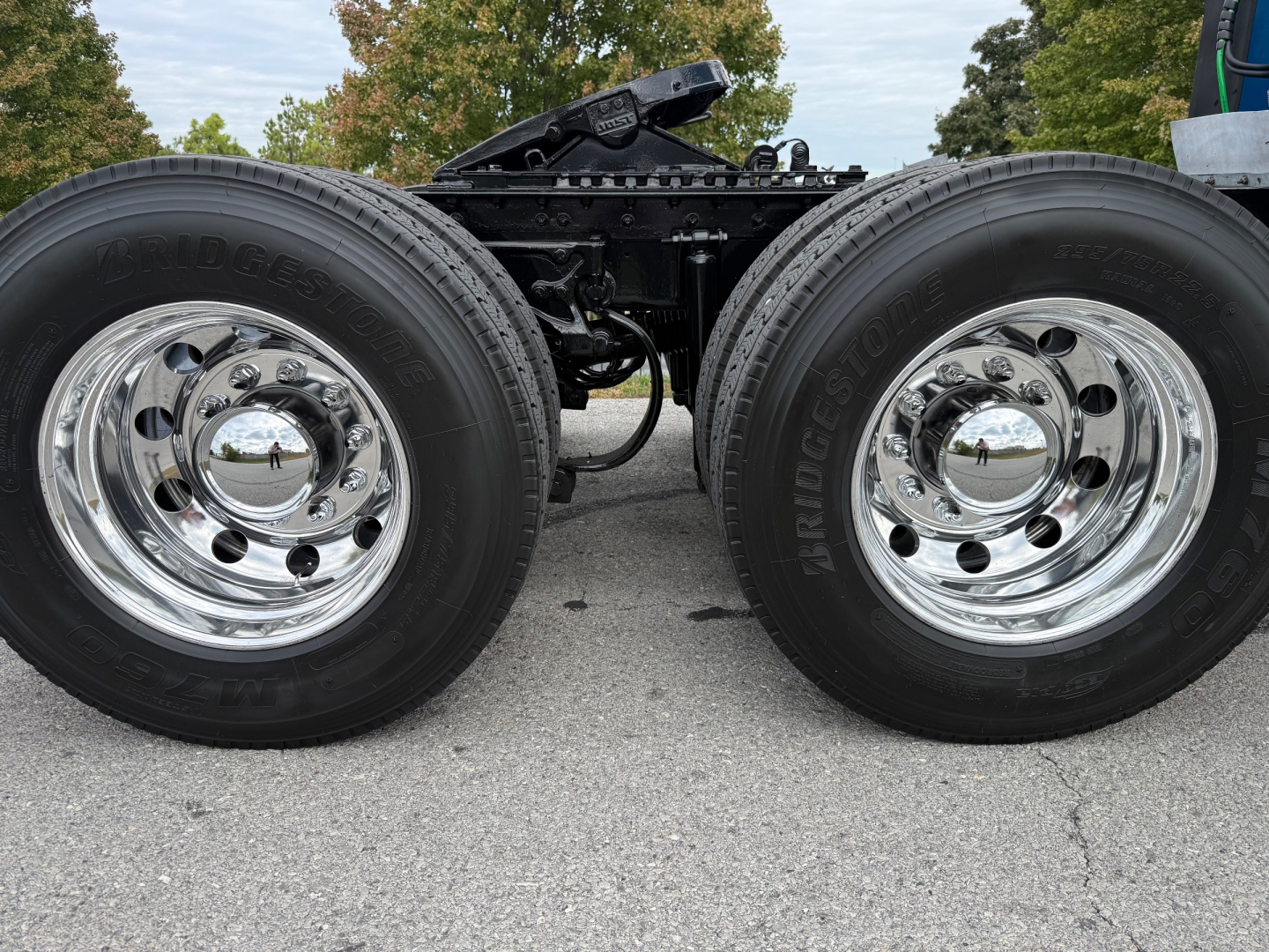 Kenworth T680 chassis with dual rear axles and chrome wheels showing tires and wheel hubs; portion of frame and fifth wheel visible.