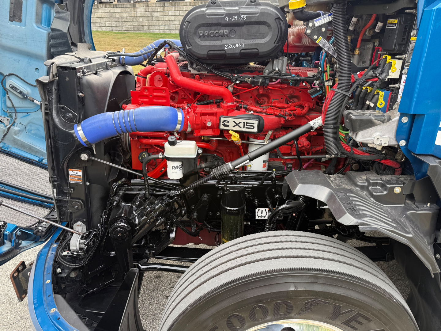 Kenworth T680 engine bay showing a red engine with blue silicone hose, label X15, radiator, and surrounding components.
