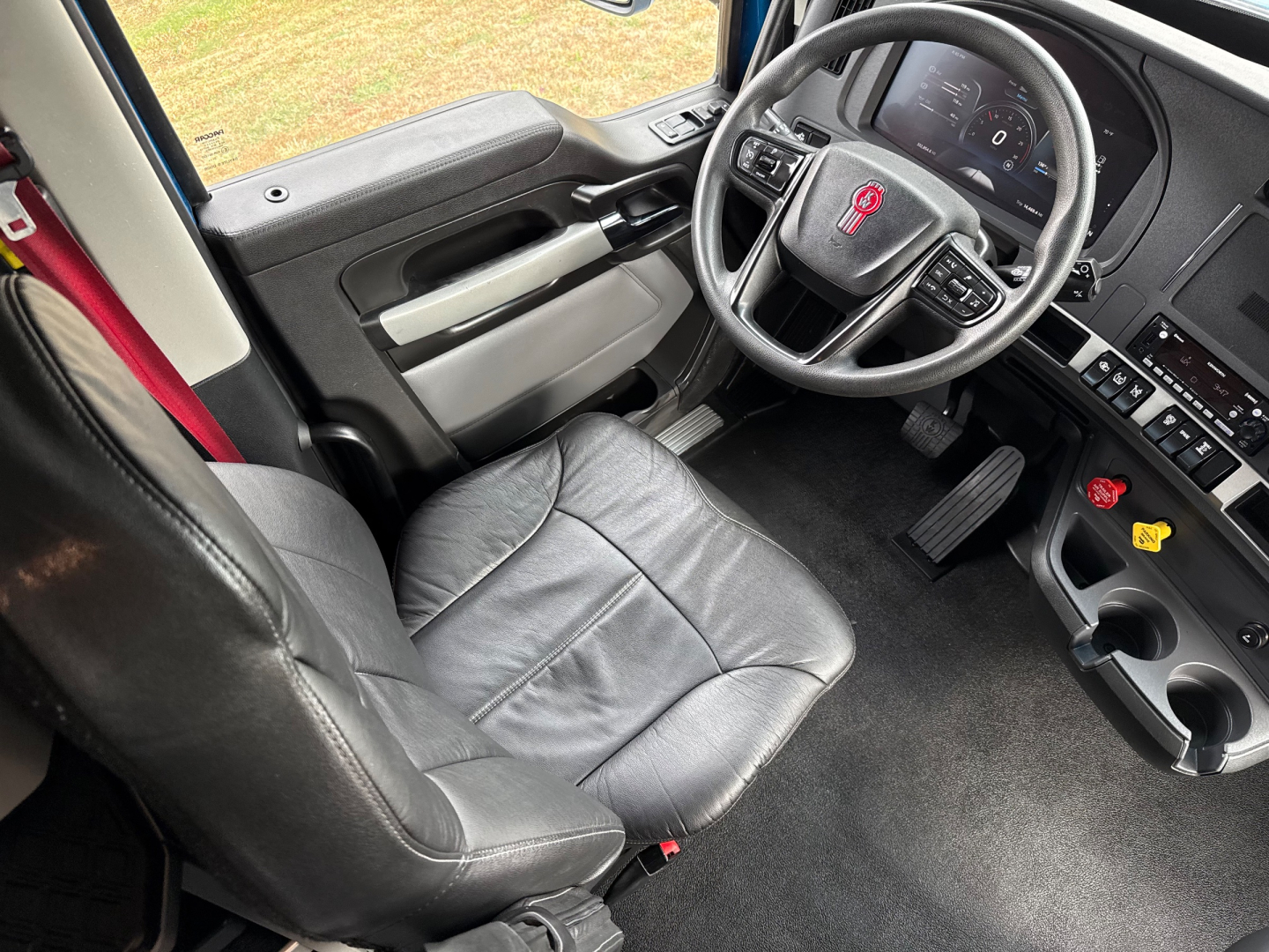 Kenworth T680 interior showing driver seat and dashboard with steering wheel and controls.